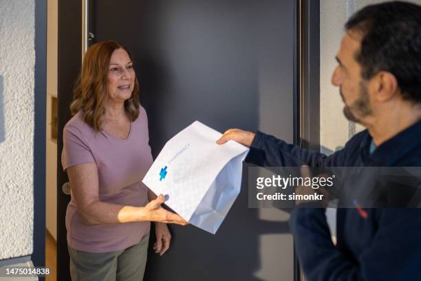 delivery person delivering medicine to woman - prescription home delivery stock pictures, royalty-free photos & images