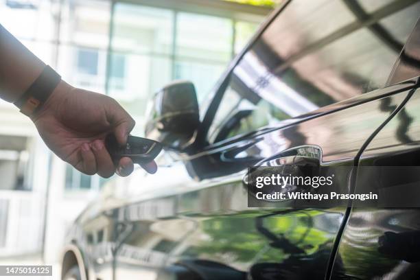 hand presses unlock on the car remote control. - car dealership test drive stock pictures, royalty-free photos & images