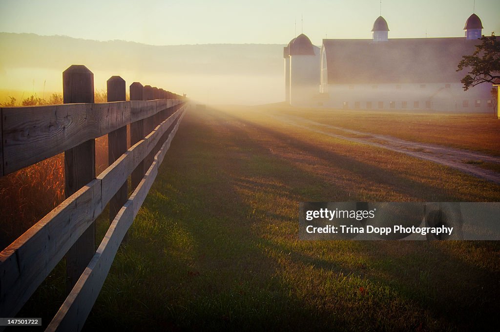 Foggy morning farm fence at sunrise