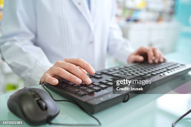 male pharmacist typing on computer keyboard - white computer keyboard stock pictures, royalty-free photos & images
