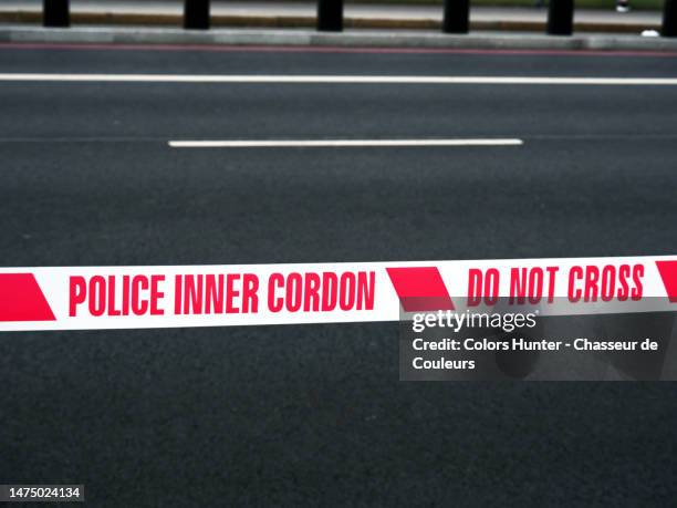 'police inner cordon - do not cross' written in red on a cordon tape and unrolled across a street in london, england, united kingdom - rope barrier stock pictures, royalty-free photos & images