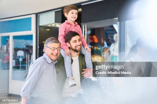 young adult man walking with father while carrying son on shoulder - grandpa son stock pictures, royalty-free photos & images
