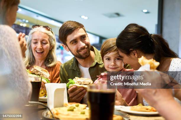 family having fun during lunch time at shopping mall's food scourt - family mall stockfoto's en -beelden