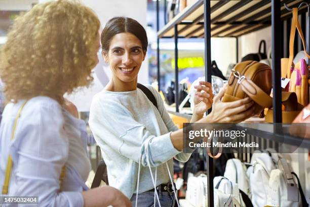 zwei erwachsene frauen, die beim einkaufen von handtaschen in einer schicken boutique stöbern - handtasche stock-fotos und bilder