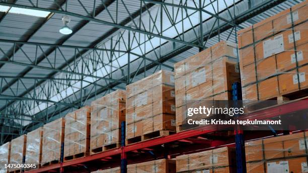 regale, die teilweise mit kisten und kisten mit fertigwaren in einem lager gefüllt sind. - transportpalette stock-fotos und bilder