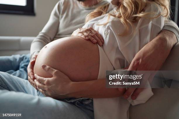 nahaufnahme eines paares, das den schwangeren bauch einer frau umarmt - sanft stock-fotos und bilder