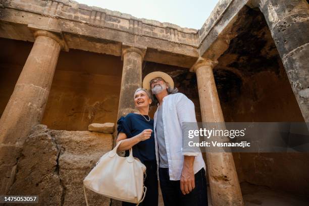 mature couple visiting cyprus, tombs of the kings necropolis on paphos - bury stock pictures, royalty-free photos & images