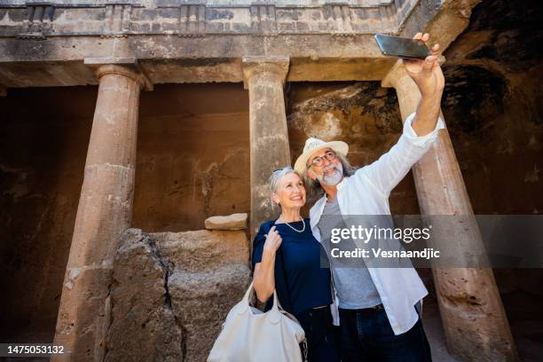 mature couple visiting cyprus, tombs of the kings necropolis on paphos - bury stock pictures, royalty-free photos & images