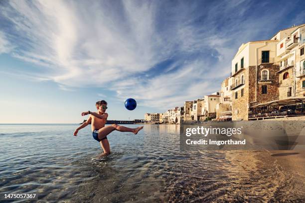 teenage boy playing with ball on on beach in small sicilian town - beach ball soccer stock pictures, royalty-free photos & images