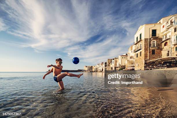 teenage boy playing with ball on on beach in small sicilian town - italy football stock pictures, royalty-free photos & images