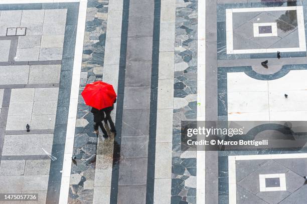 two people walking with a red umbrella - milan aerial stock pictures, royalty-free photos & images