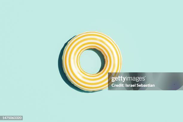 digitally generated image of a yellow inflatable ring seen from above on blue background with copy space. summer concept. - inflatable ring stock-fotos und bilder