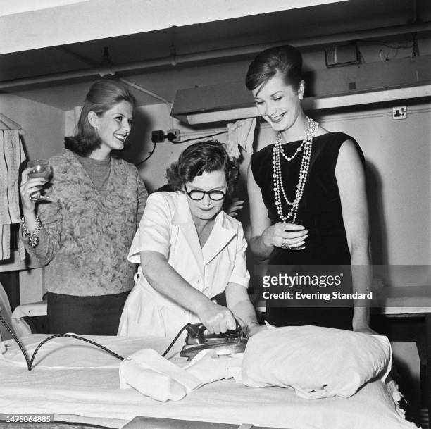 Models Paulene Stone and Daphne Abrams pictured backstage at a London fashion show where Teresa Cartnell is ironing an item of clothing on October...