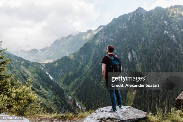 man with backpack looking at carpathian mountains in transylvania, romania - romania mountain stock pictures, royalty-free photos & images