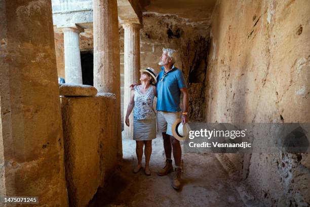 mature couple visiting cyprus, tombs of the kings necropolis on paphos - paphos stock pictures, royalty-free photos & images