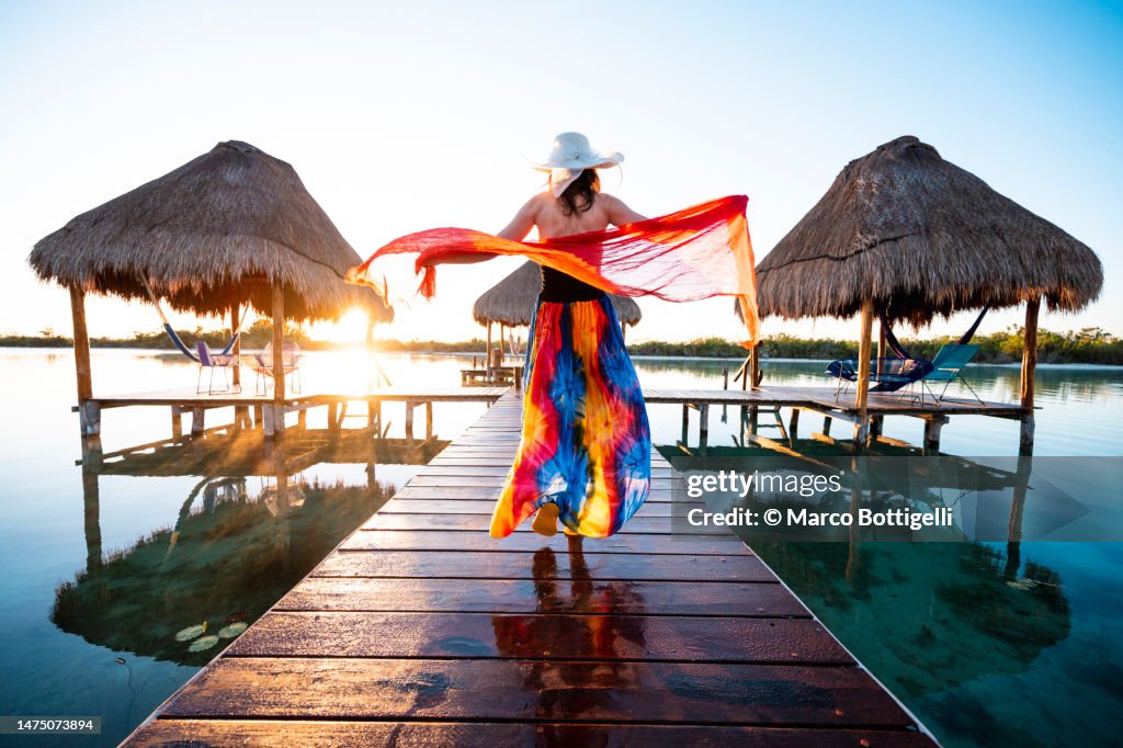 Woman playing with red sarong on a pier, Mexico
