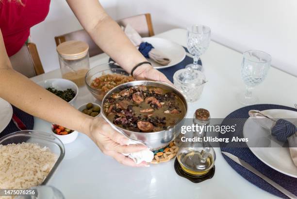 frau serviert mittagessen - brazilian feijoada dish stock-fotos und bilder