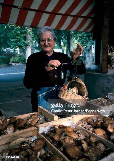 Stallholder weighs a punnet of wild mushrooms for sale on a stall at a food market on a street in the centre of the city of Brive-la-Gaillarde in the...