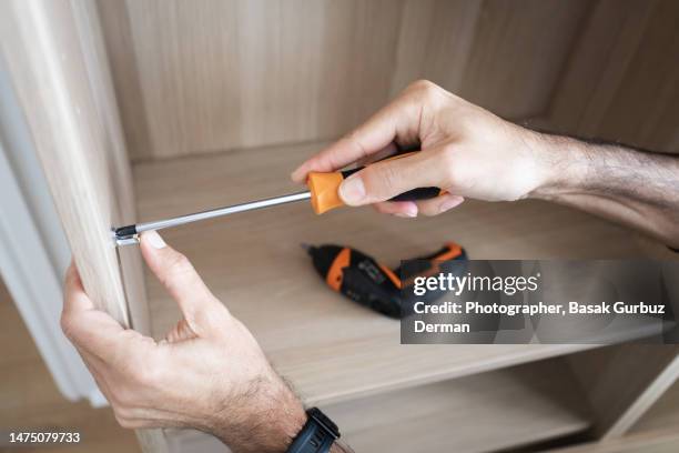 a man assembling a cabinet - screwdriver stock pictures, royalty-free photos & images