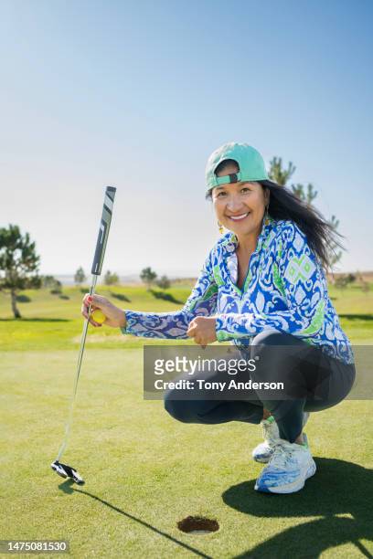 portrait of senior woman golfing on putting green - playing golf stock-fotos und bilder