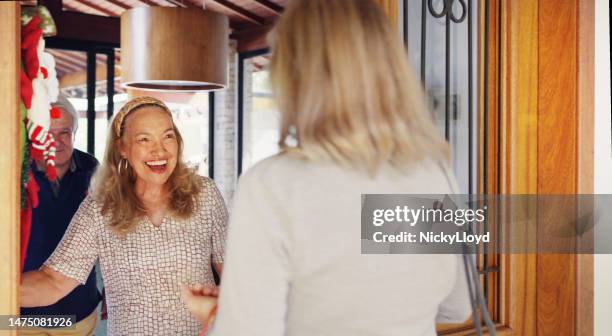 smiling seniors greeting friends at their home for a christmas get together - open door party stock pictures, royalty-free photos & images