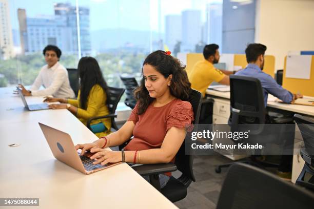 cheerful mid adult woman along with her coworkers working on a laptop in an office cubicle - digital india stock pictures, royalty-free photos & images