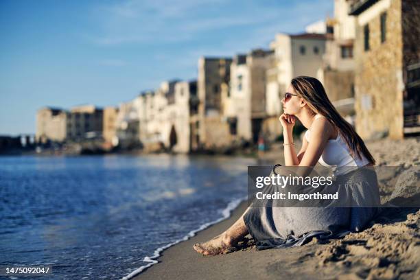 linda adolescente sentada en la playa en una pequeña ciudad siciliana - southern italy fotografías e imágenes de stock