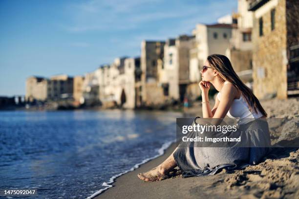 cute teenage girl sitting on the beach in small sicilian town - southern italy stock pictures, royalty-free photos & images