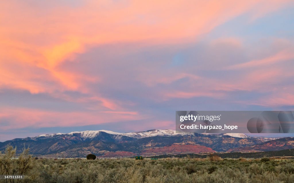 Sunset clouds above snowy redrock mountains