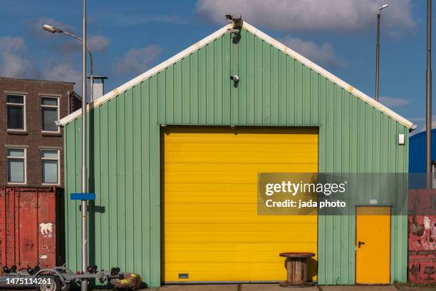 green garage with steel yellow roller shutter - yellow door stock pictures, royalty-free photos & images