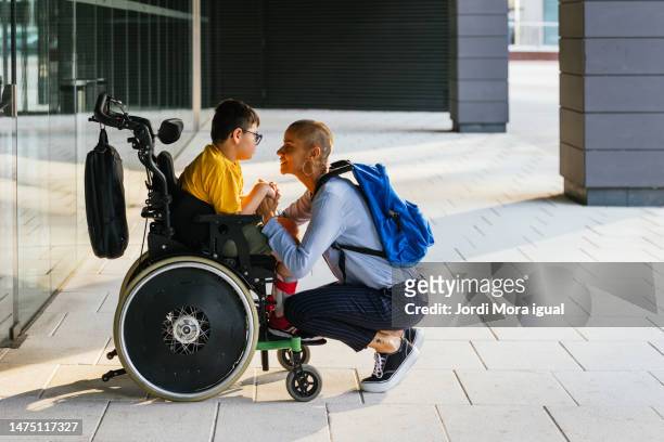 child in wheelchair listening attentively to his mother as she talks to him. - quadriplegic - fotografias e filmes do acervo