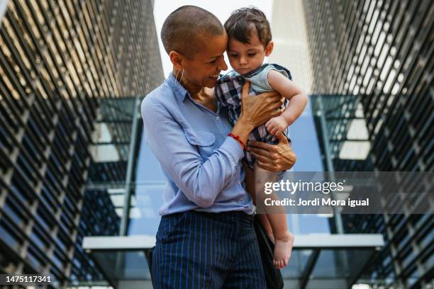 a proud mother and her baby embrace, smiling as they share a moment of love in the city life. - human prosperity stock pictures, royalty-free photos & images