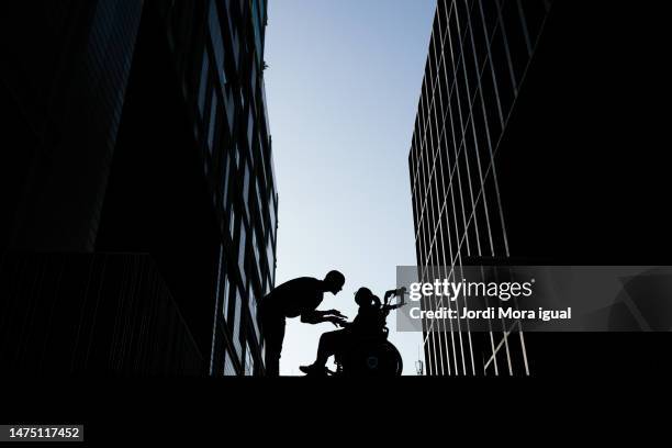 mother bending down talking to her son with tetraplegia who is sitting in a wheelchair. - quadriplegic - fotografias e filmes do acervo