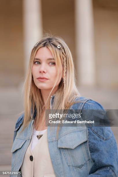 Natalia Verza wears hair clips, a blue denim oversized jacket with shoulder pads from Balmain, a white t-shirt from Prada, a waistcoat, during a...