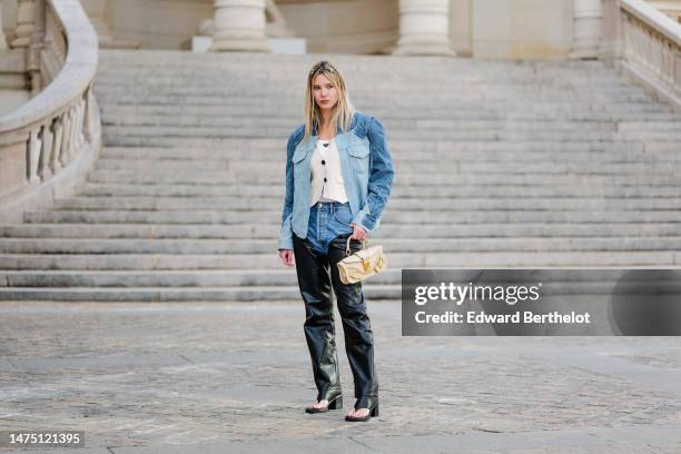 Natalia Verza wears a blue denim oversized jacket with shoulder pads from Balmain, a white t-shirt from Prada, a waistcoat, a beige leather bag with...