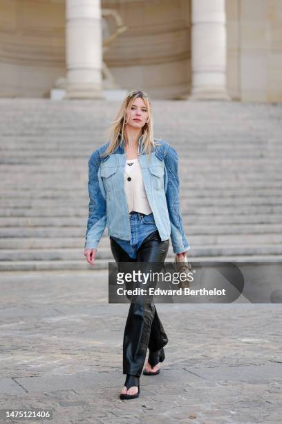 Natalia Verza wears a blue denim oversized jacket with shoulder pads from Balmain, a white t-shirt from Prada, a waistcoat, a beige leather bag with...