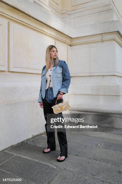 Natalia Verza wears a blue denim oversized jacket with shoulder pads from Balmain, a white t-shirt from Prada, a waistcoat, a beige leather bag with...