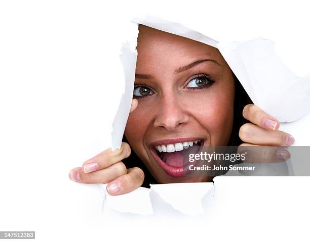 happy young woman ripping through paper wall - breaking through wall stockfoto's en -beelden