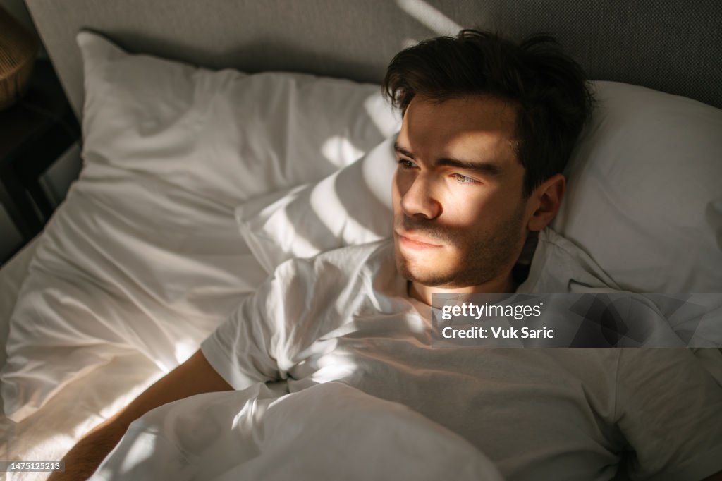 Mann, der in einem Bett liegt und aufwacht