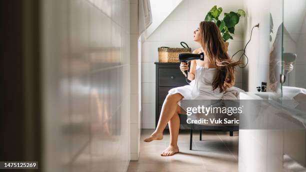 woman wrapped in a towel drying her hair in the bathroom. - drying hair stock pictures, royalty-free photos & images