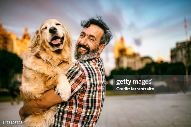 mature man hugs golden retriever - man and dog portrait stock pictures, royalty-free photos & images