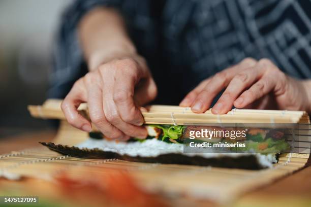 close up photo of woman hands rolling up sushi - nori stock pictures, royalty-free photos & images