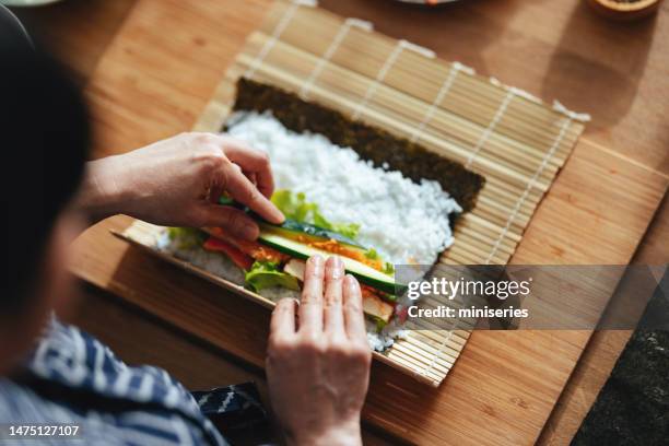 close up photo of woman hands rolling up sushi - hand roll stock pictures, royalty-free photos & images