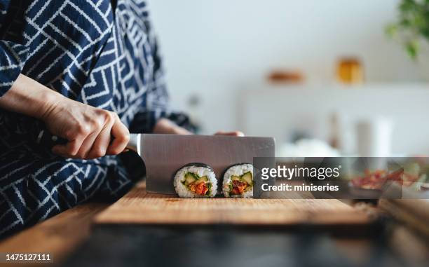 close up photo of woman hands cutting sushi rolls - sushi chef stock pictures, royalty-free photos & images