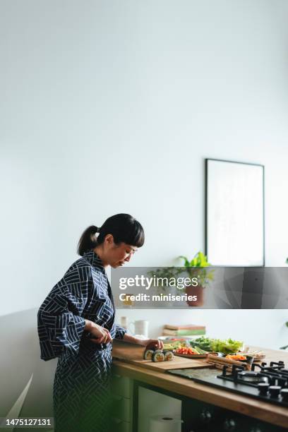 happy woman cutting sushi rolls in the kitchen - knife kitchen stock pictures, royalty-free photos & images