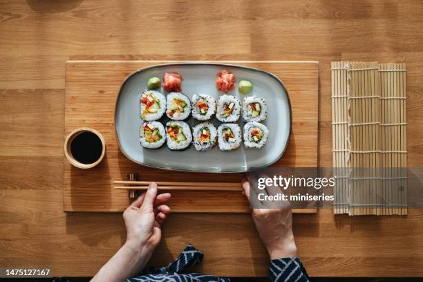 photo en gros plan de mains de femme servant des rouleaux de sushi sur la table - nori photos et images de collection
