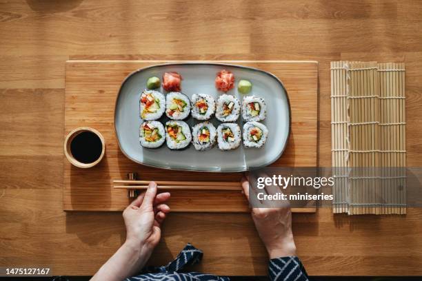 close up photo of woman hands serving sushi rolls on the table - asian cuisine japanese cuisine stock pictures, royalty-free photos & images