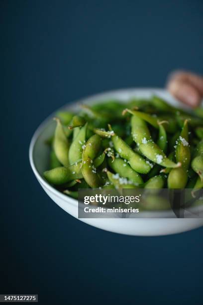 photo en gros plan d’une femme tenant une assiette avec des haricots edamame cuits - cuisine japonaise photos et images de collection