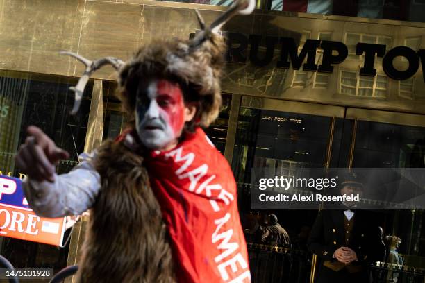 Trump Tower emploee watches a demonstrator who identified himself as Steven Daniel Wolverton dressed like the Q-Anon shaman stands outside Trump...