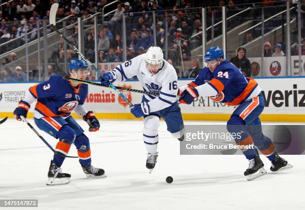 Mitchell Marner of the Toronto Maple Leafs skates against Adam Pelech and Scott Mayfield of the New York Islanders during the first period at the UBS...